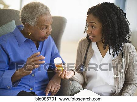 Stock Image - Nurse explaining medication to woman. Fotosearch