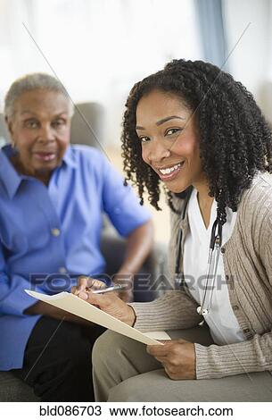 Stock Image - Nurse giving woman checkup. Fotosearch