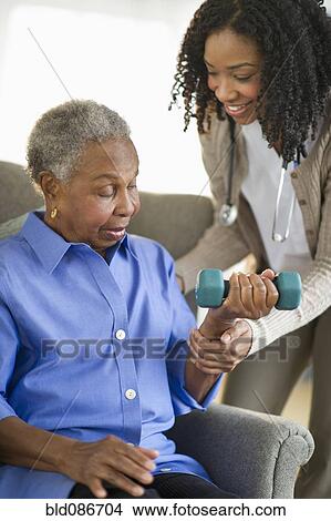 Picture - Nurse helping woman exercise with dumbbells. Fotosearch