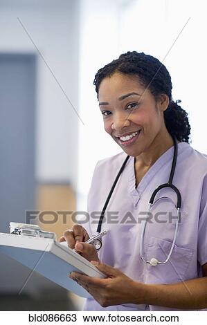 Stock Image - Nurse writing in medical record in hospital. Fotosearch