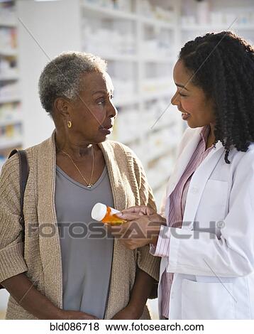Stock Photo - Pharmacist explaining medication to woman. Fotosearch