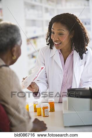 Stock Photograph - Pharmacist handing medication to woman. Fotosearch