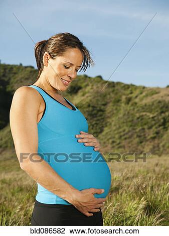 Stock Image - Pregnant Hispanic woman caressing her stomach. Fotosearch
