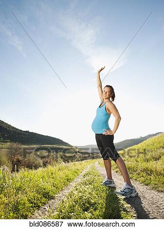 Stock Photo - Pregnant Hispanic woman exercising in remote area. Fotosearch