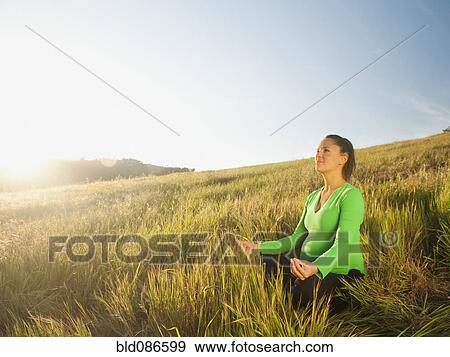 Stock Photo - Pregnant Hispanic woman practicing yoga in field. Fotosearch