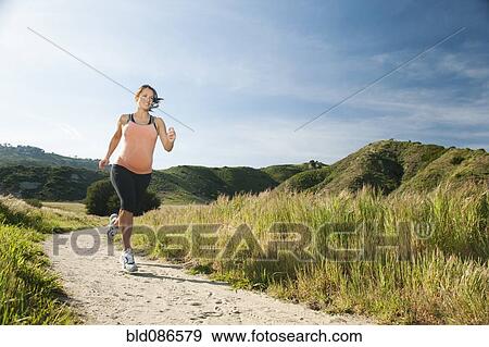 Stock Photo - Pregnant Hispanic woman running in remote area. Fotosearch