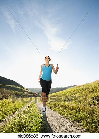 Stock Photograph - Pregnant Hispanic woman running in remote area. Fotosearch