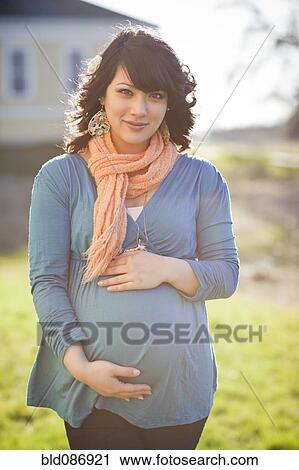 Stock Image - Pregnant mixed race woman holding stomach. Fotosearch