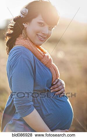 Pregnant mixed race woman holding stomach View Large Photo Image Stock Photo - Pregnant mixed race woman holding stomach. Fotosearch