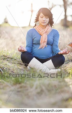 Picture - Pregnant mixed race woman practicing yoga in field. Fotosearch