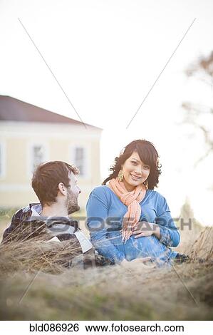 Pregnant woman sitting in field with husband View Large Photo Image Stock Photograph - Pregnant woman sitting in field with husband. Fotosearch