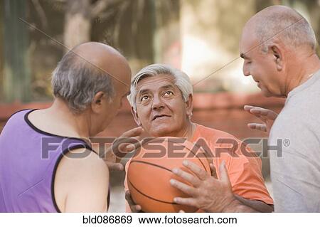 Stock Photo - Senior Chilean men playing basketball together. Fotosearch