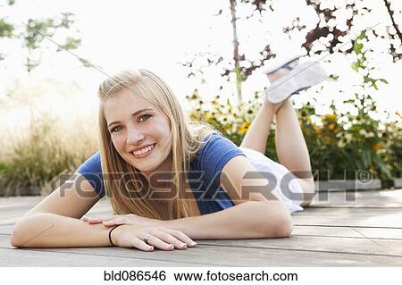 Stock Photograph - Smiling Caucasian teenager laying on deck. Fotosearch