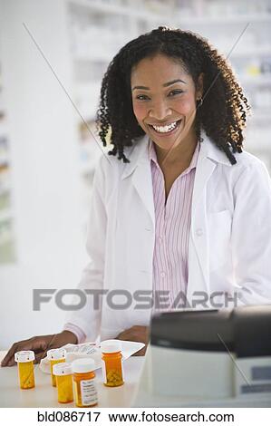 Stock Photo - Smiling pharmacist working with medication. Fotosearch