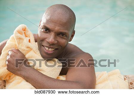 Stock Image - African American man drying off with towel at poolside. Fotosearch