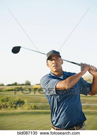 Stock Photography - Black golfer swinging golf club. Fotosearch