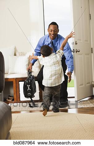 Picture - Businessman returning from work being greeted by son. Fotosearch