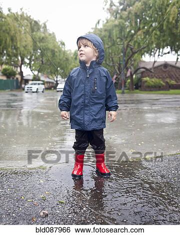 Stock Photograph - Caucasian boy standing in rain. Fotosearch