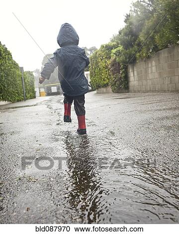 Caucasian boy walking in rain puddle View Large Photo Image Stock Image - Caucasian boy walking in rain puddle. Fotosearch
