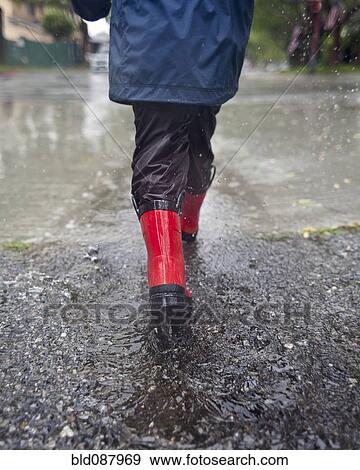 Stock Photo - Caucasian boy walking in the rain. Fotosearch