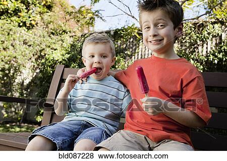 Stock Photo - Caucasian brothers eating popsicles. Fotosearch