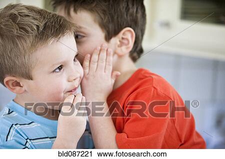 Stock Image - Caucasian brothers whispering together. Fotosearch