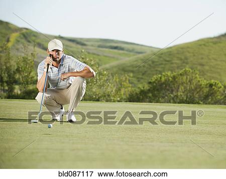 Stock Photo - Caucasian golfer checking the ground on golf course. Fotosearch