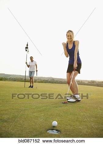 Stock Image - Caucasian golfer cheering on golf course. Fotosearch