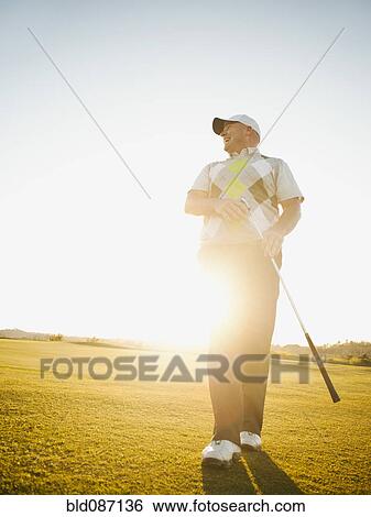 Stock Photograph - Caucasian man walking on golf course with golf club. Fotosearch