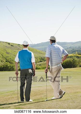 Stock Photograph - Caucasian men playing golf together on golf course. Fotosearch