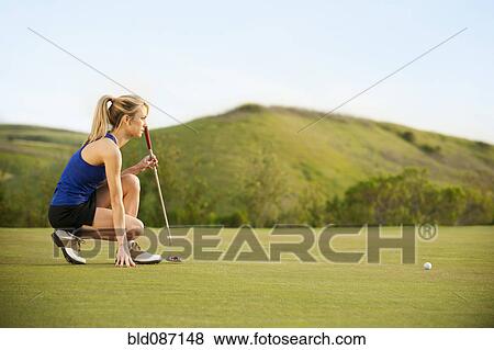 Stock Photo - Caucasian woman checking ground on golf course. Fotosearch
