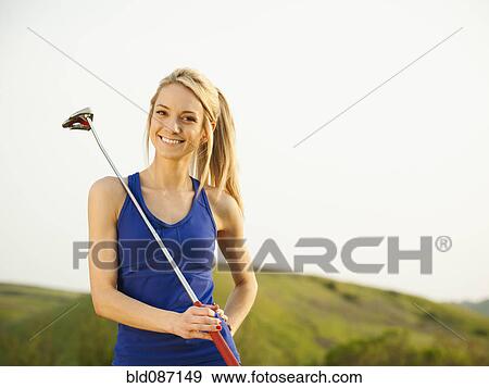 Stock Photo - Caucasian woman holding gold club. Fotosearch