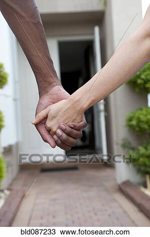 Stock Image - Close up of couple holding hands. Fotosearch