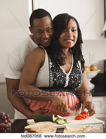 Stock Photograph - Couple cooking together in kitchen. Fotosearch