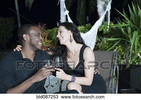 Couple toasting with red wine at night View Large Photo Image Stock Image - Couple toasting with red wine at night. Fotosearch