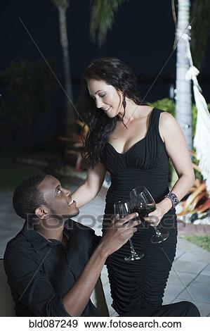 Couple toasting with red wine on patio at night View Large Photo Image Stock Photo - Couple toasting with red wine on patio at night. Fotosearch
