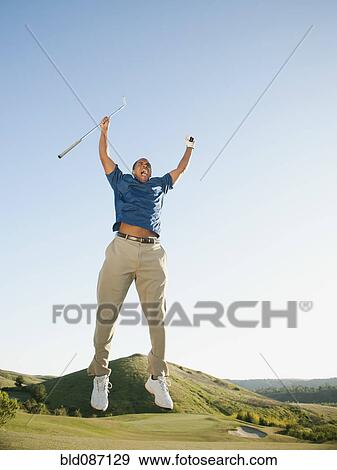 Stock Photo - Excited Black golfer jumping in mid-air on golf course. Fotosearch