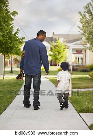 Stock Image - Father and son walking with baseball glove and bat. Fotosearch