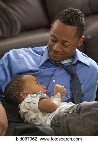 Stock Image - Father playing with son on living room floor. Fotosearch