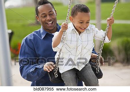 Stock Photography - Father pushing son on swing. Fotosearch
