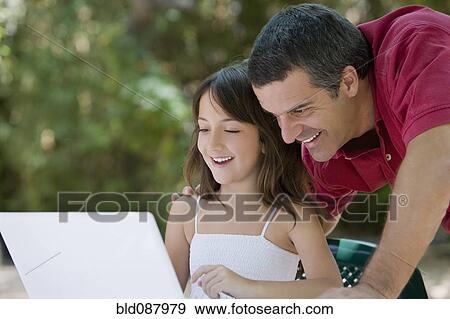 Hispanic father watching daughter use laptop View Large Photo Image Stock Photo - Hispanic father watching daughter use laptop. Fotosearch