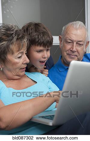 Stock Image - Hispanic grandparents and grandson looking at laptop. Fotosearch
