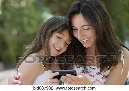 Hispanic mother and daughter text messaging on cell phone View Large Photo Image Stock Image - Hispanic mother and daughter text messaging on cell phone. Fotosearch