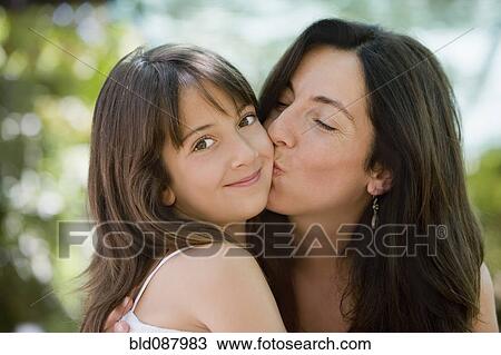 Stock Image - Hispanic mother kissing daughter. Fotosearch