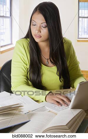 Stock Image - Hispanic student doing homework on laptop. Fotosearch