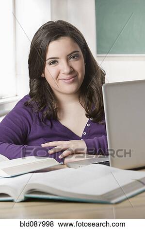 Stock Photo - Hispanic teenage girl doing homework with laptop. Fotosearch