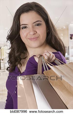 Stock Photograph - Hispanic teenage girl holding shopping bags. Fotosearch