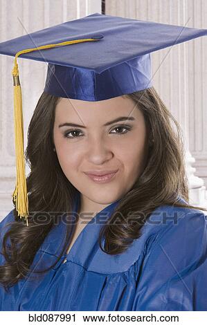 Stock Image - Hispanic teenage girl in graduation cap and gown. Fotosearch