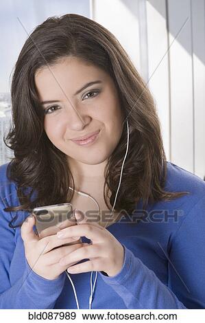 Stock Photo - Hispanic teenage girl listening to mp3 player. Fotosearch