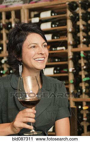 Stock Image - Hispanic woman drinking red wine. Fotosearch